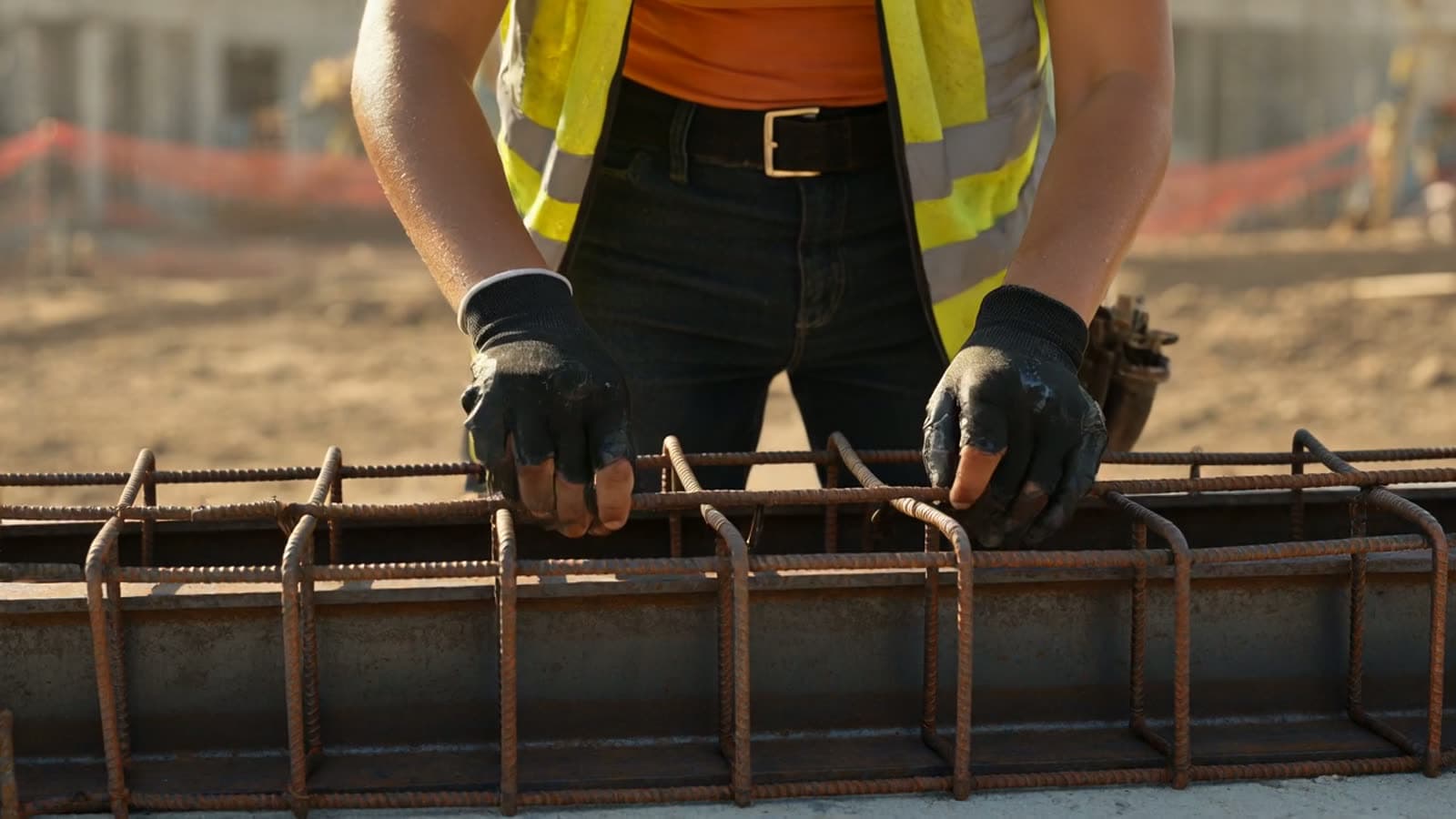 Construction professional tying reinforcing steel on an active job site