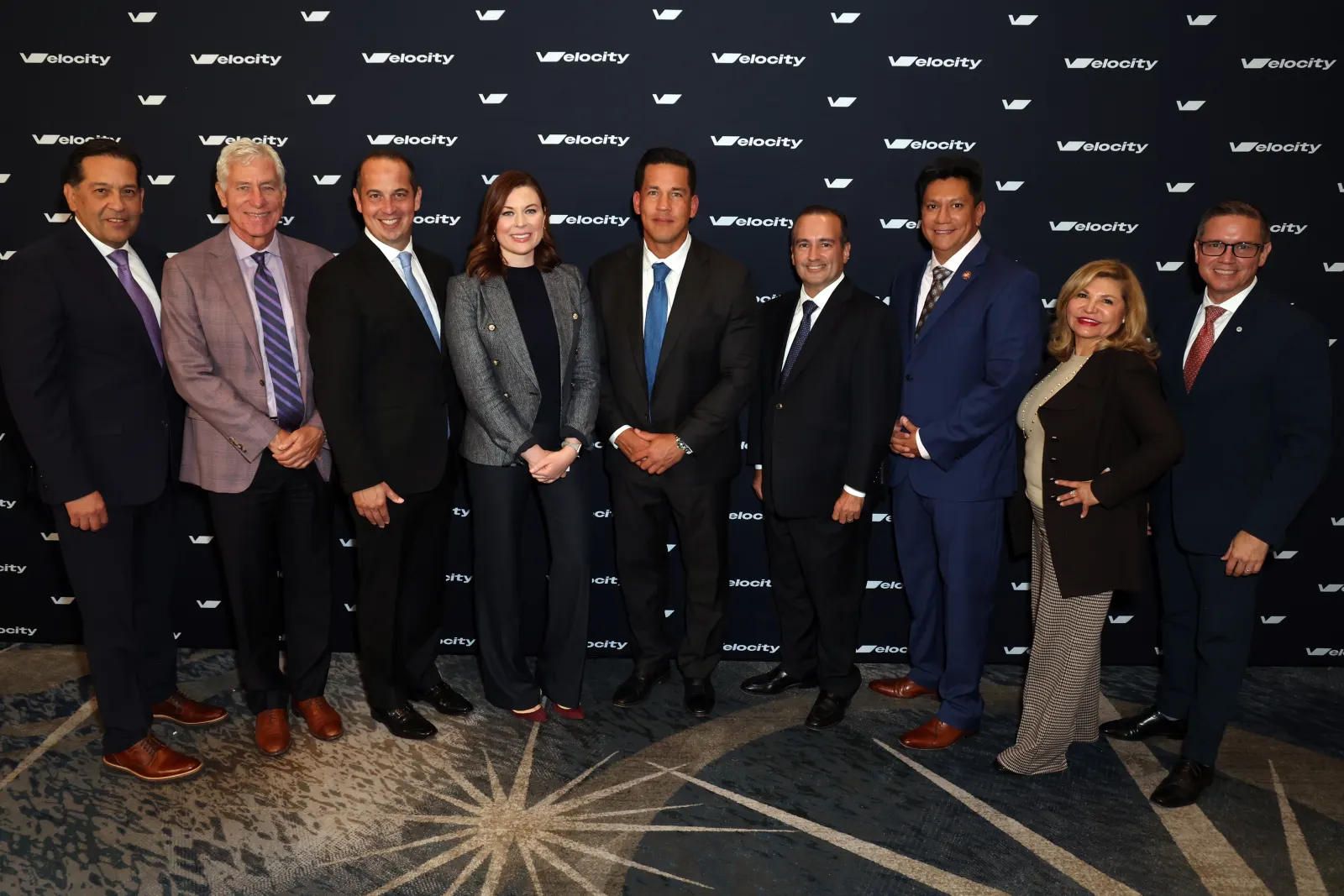 Velocity 2025 speakers and organizers gather in front of the event backdrop