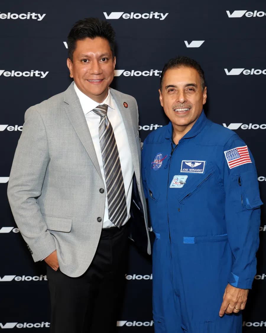 A Velocity attendee with astronaut José Hernández in front of the event backdrop