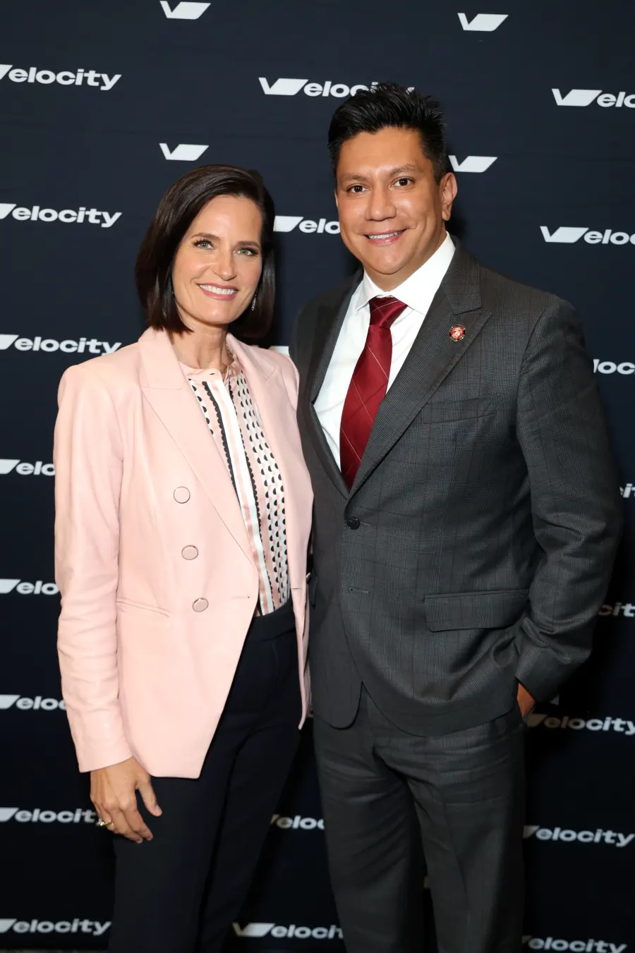 Two Velocity attendees in front of the event backdrop